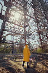 young man in yellow protective suit standing near military secret object antenna radar Duga in...