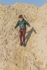 A little boy is climbing a sand mountain.