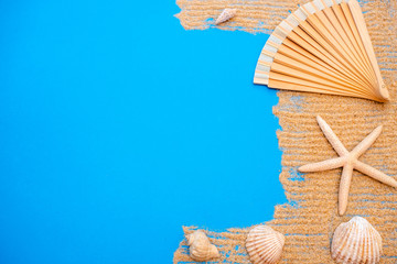 Summer time concept with sea shells and starfish on a blue wooden background and sand.