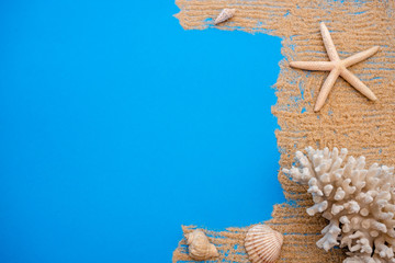 Summer time concept with sea shells and starfish on a blue wooden background and sand.