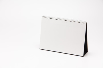 A white paper calendar stands on the table in photo