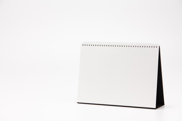 A white paper calendar stands on the table in photo