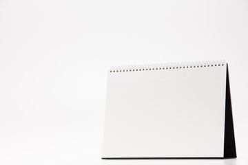 A white paper calendar stands on the table in photo