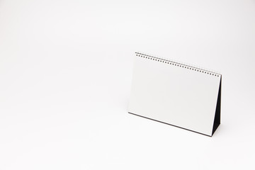 A white paper calendar stands on the table in photo