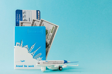 Passport, dollars, plane and air ticket on a blue background. Travel concept, copy space