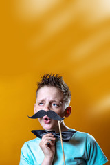 boy in a light t-shirt with a mustache and a bow sings and says funny
