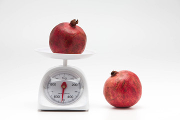 Red pomegranate on scales on a white