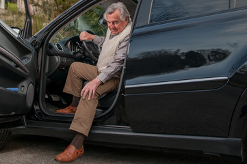 Senior man having  pain in hte knee while getting out of his car