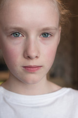 Cute Caucasian blond young girl angry frowns, studio portrait  on brown background