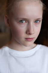 Cute Caucasian blond young girl angry frowns, studio portrait  on brown background