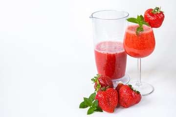 Strawberry smoothie in a glass on a high leg decorated with strawberries and mint on a white background. Strawberry season.Healthy lifestyle.