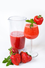 Strawberry smoothie in a glass on a high leg decorated with strawberries and mint on a white background. Strawberry season.Healthy lifestyle.