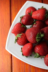 Strawberries in a plate on living coral wooden background