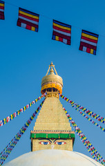 Buddhist prayer flags in front of the dome and gold spire of Bodhnath Stupa, Kathmandu, Nepal