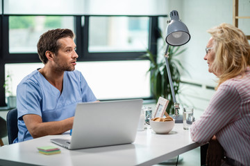 Fototapeta premium General practitioner talking to mature woman at doctor's office.