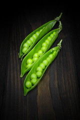 Green peas on a brown wooden background.