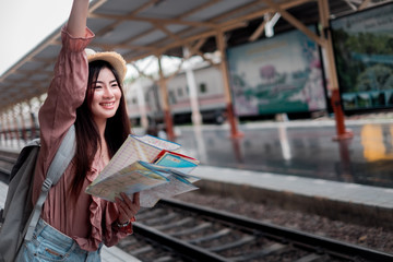Smiling woman traveler with backpack holding world map planning vacation on holiday relaxation at the train station,relaxation concept, travel concept