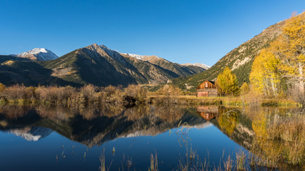 Fototapeta na wymiar Old cabin by lake in Autumn colors