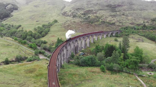 Steam Train crossing the Glenfinnan Viaduct, aerial view by drone - Scotland, UK