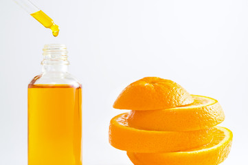 Vitamin C serum in cosmetic bottle with dropper and sliced orange on white background. Organic SPA...