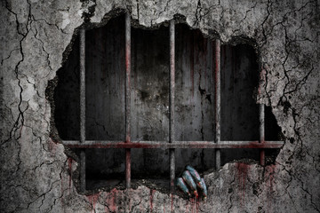 Hand of devil has stains and drops of blood and holding the damaged grungy crack and broken concrete wall in old prison metal bars, Bloody background scary and horror