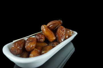 Group of dates fruits on white container isolated on black background