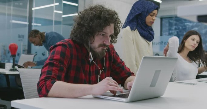 Multiethnics business team of software developers programming together using laptop at modern startup office