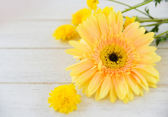 Yellow mum flowers and gerbera spring flowers on white wooden