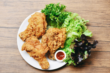 Fried chicken crispy on white plate with ketchup and salad lettuce vegetable on wooden