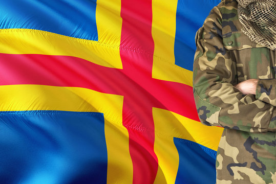 Crossed arms soldier with national waving flag on background - Aland Islands Military theme.