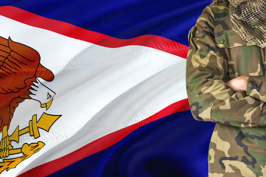 Crossed arms soldier with national waving flag on background - American Samoa Military theme.
