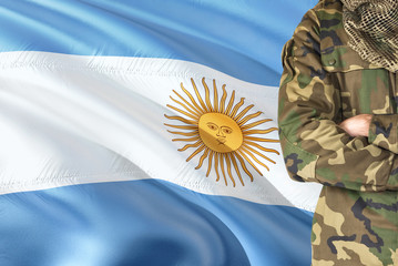 Crossed arms Argentine soldier with national waving flag on background - Argentina Military theme.