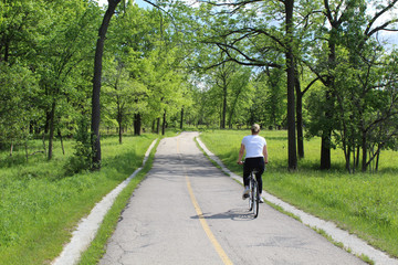 Woman riding a bicycle on the North Branch Trail at Miami Woods in Morton Grove,  Illinois