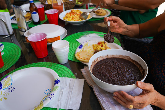 Las personas disfrutan un rico desayuno venezolano con arepas, caraotas negras, huevos, queso blanco, jugo de naranja y café.