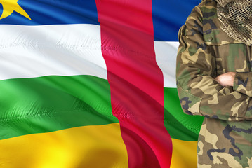 Crossed arms soldier with national waving flag on background - Central African Republic Military theme.