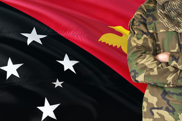 Crossed arms soldier with national waving flag on background - Papua New Guinea Military theme.