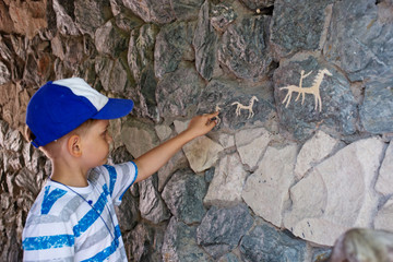 Ancient cave paintings and little boy. Bronze Age culture dated to the first half of the 2nd...