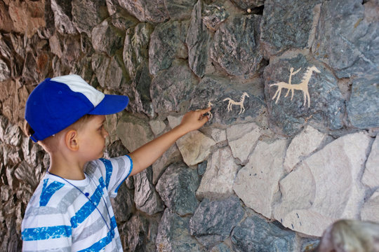 Ancient cave paintings and little boy. Bronze Age culture dated to the first half of the 2nd millennium BC.