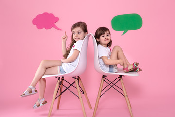 Two little girls on colored background with speech icons
