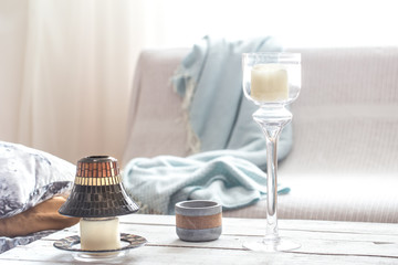 Beautiful burning candles with bottles on white table