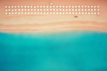 Aerial top view on the beach. Umbrellas, sand and sea waves