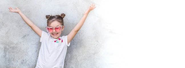 Cheerful little girls on gray textured background. Outdoor portrait little girl. Gray textured wall background.