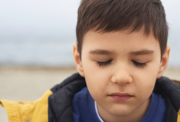 young boy with closed eyes on the background of the sea