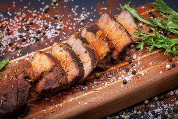 Oven Roasted Pork sprinkled  with spices and garnished with frisee endive leaves on wooden cutting...
