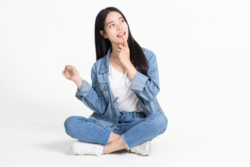 Thinking asian woman sitting on floor isolated on white background.Asian female model smiling looking up.woman pointing fingers away while sitting on a floor with legs crossed isolated