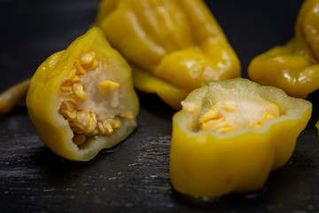 Pickled Golden Greek Peppers, Pepperoncini or Friggitelli (sweet Italian chili pepper) on natural stone background. Capsicum annuum.