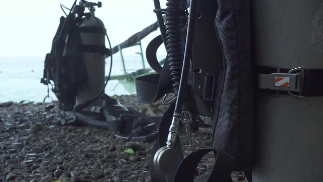 Scuba diving equipment air diver tank and gear on sea shore. Man scuba diver preparing diving equipment to dive in sea water.