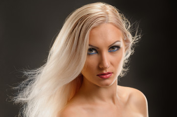 Young blonde woman with healthy straight hair showing shoulder