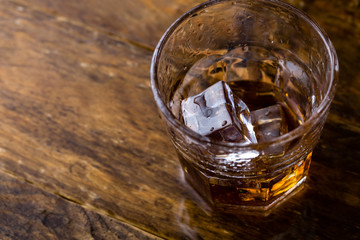 Glass of whiskey on wooden background, close up