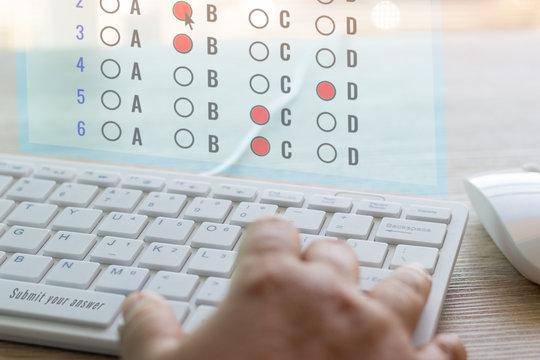 Dry hand of adult student using white keyboard on table to do test examination with multiple choice questions on virtual screen at home. Education futuristic technology and Lifelong learning concept.